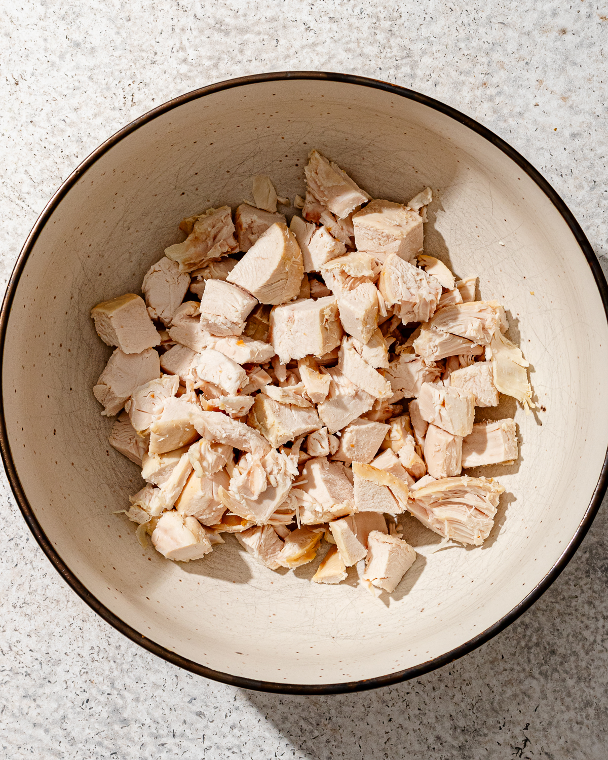 Cooked chicken cut up in a bowl for high protein chicken salad.