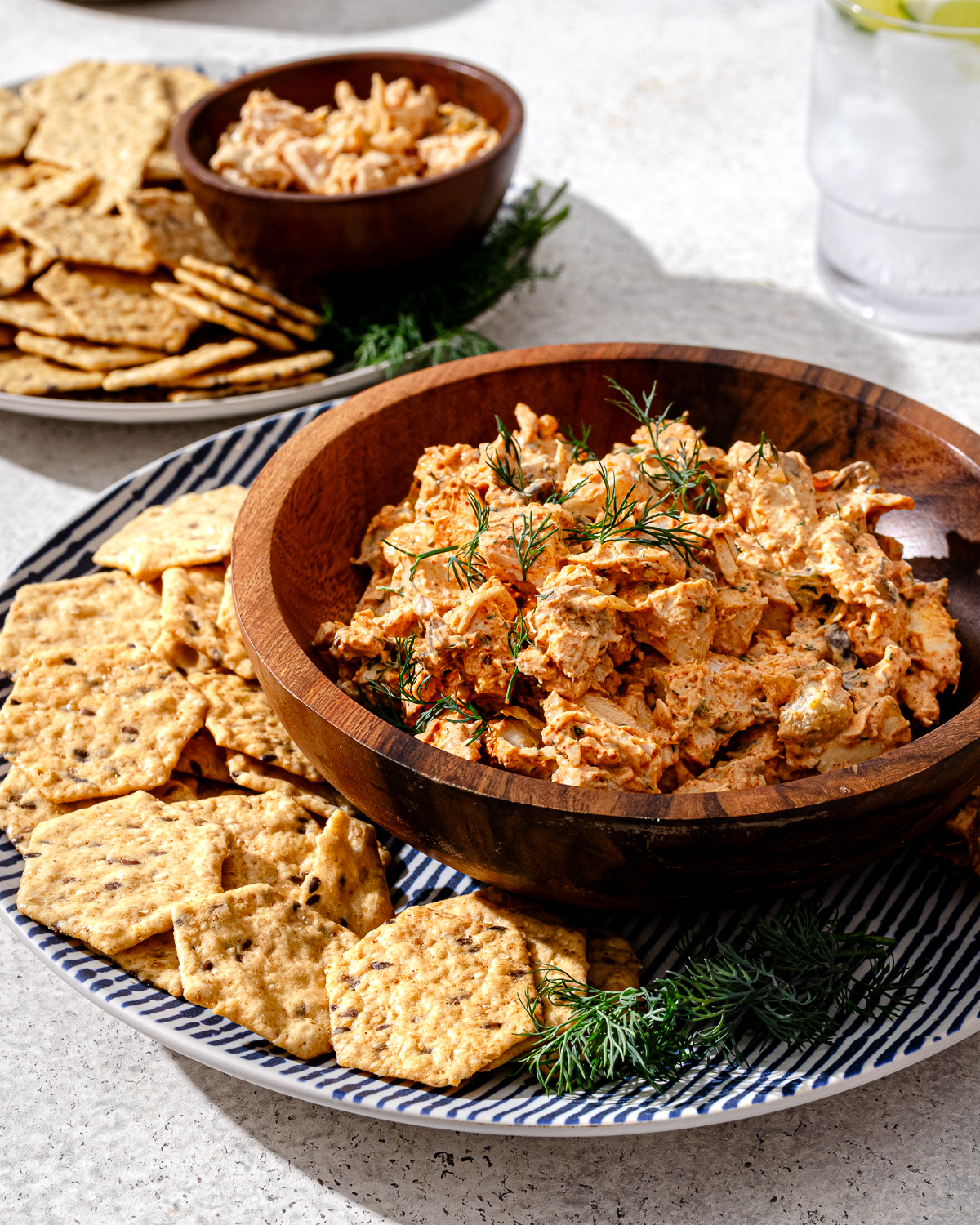 A bowl of high protein chicken salad with crackers on a gray marble surface.