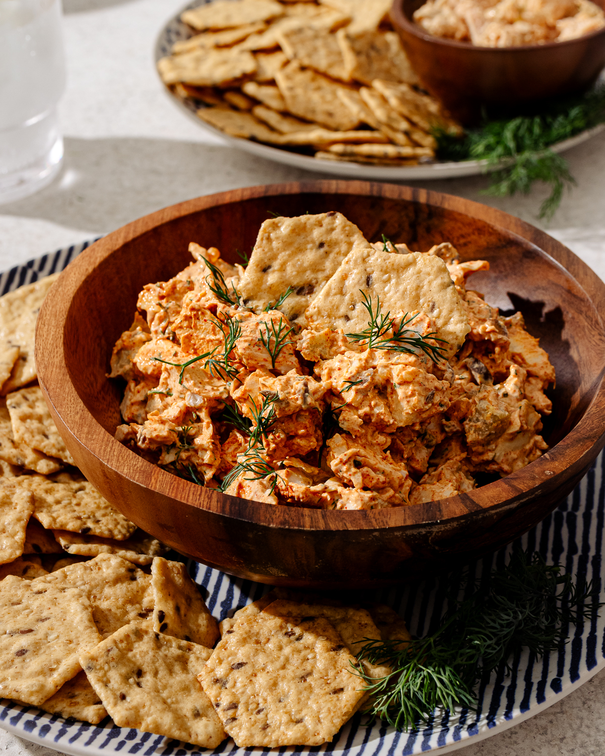 High protein chicken salad in a wooden bowl with crackers and garnish.