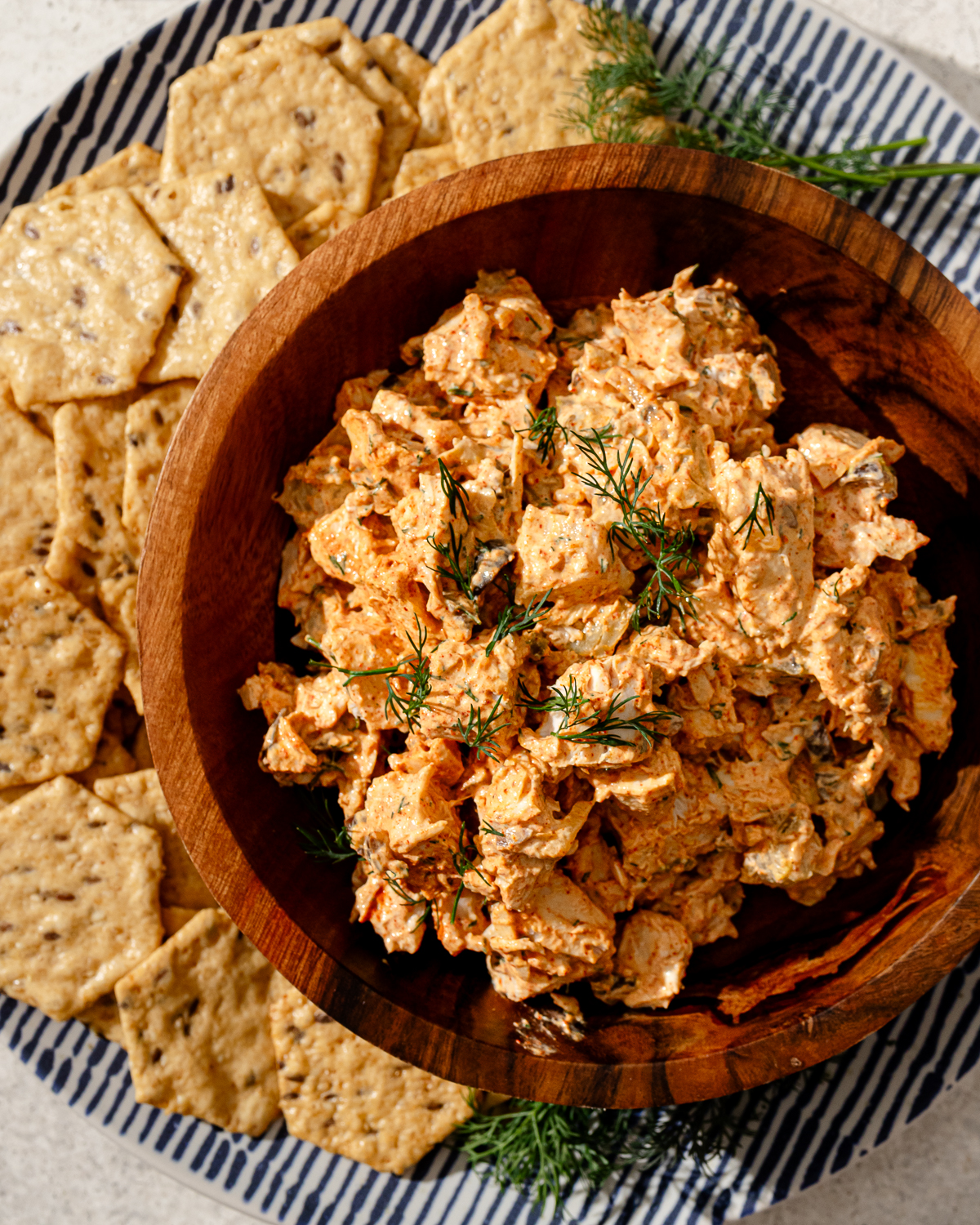 High protein chicken salad in a wooden bowl with crackers and garnish.