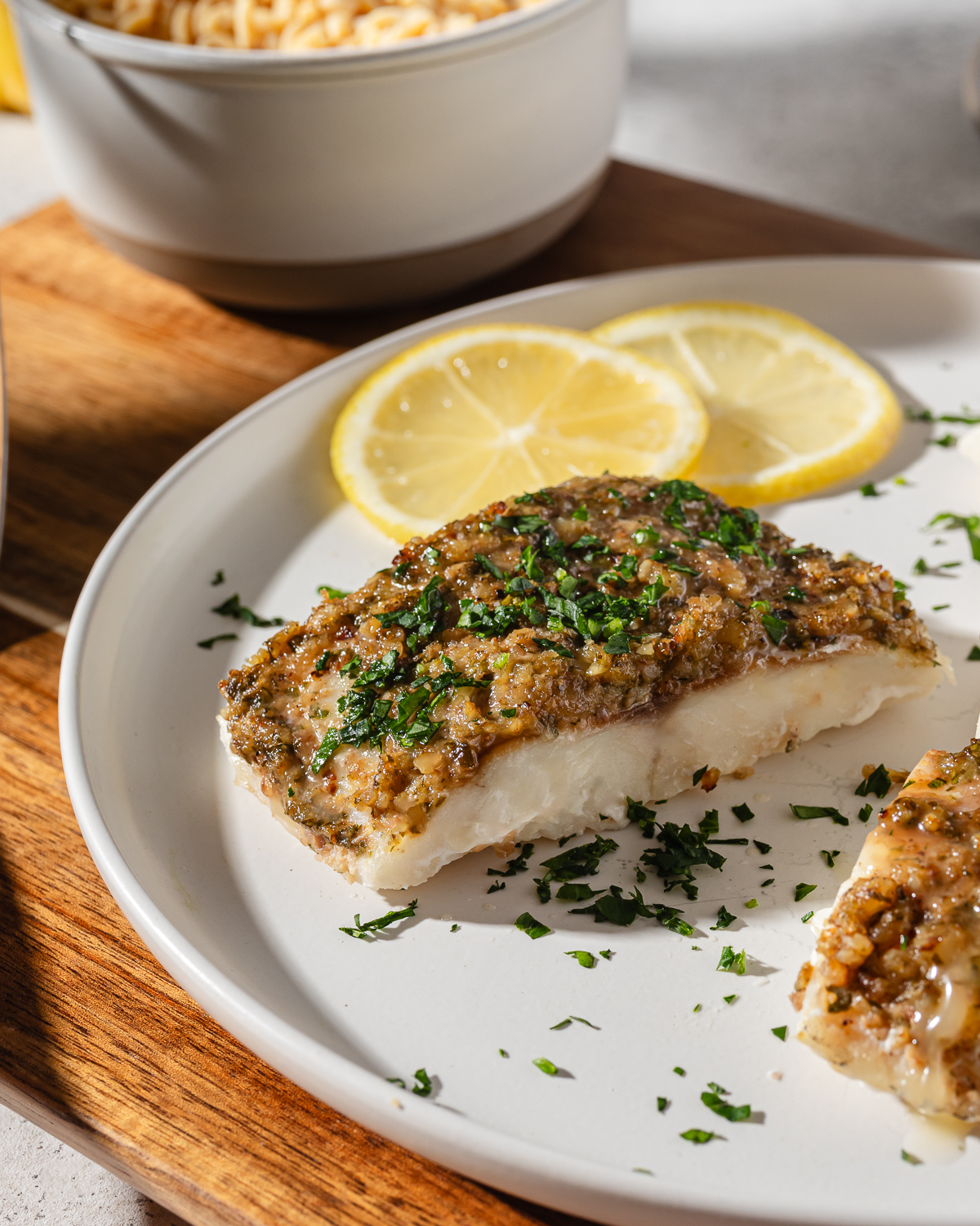 Baked Mediterranean cod on a white plate with lemon.