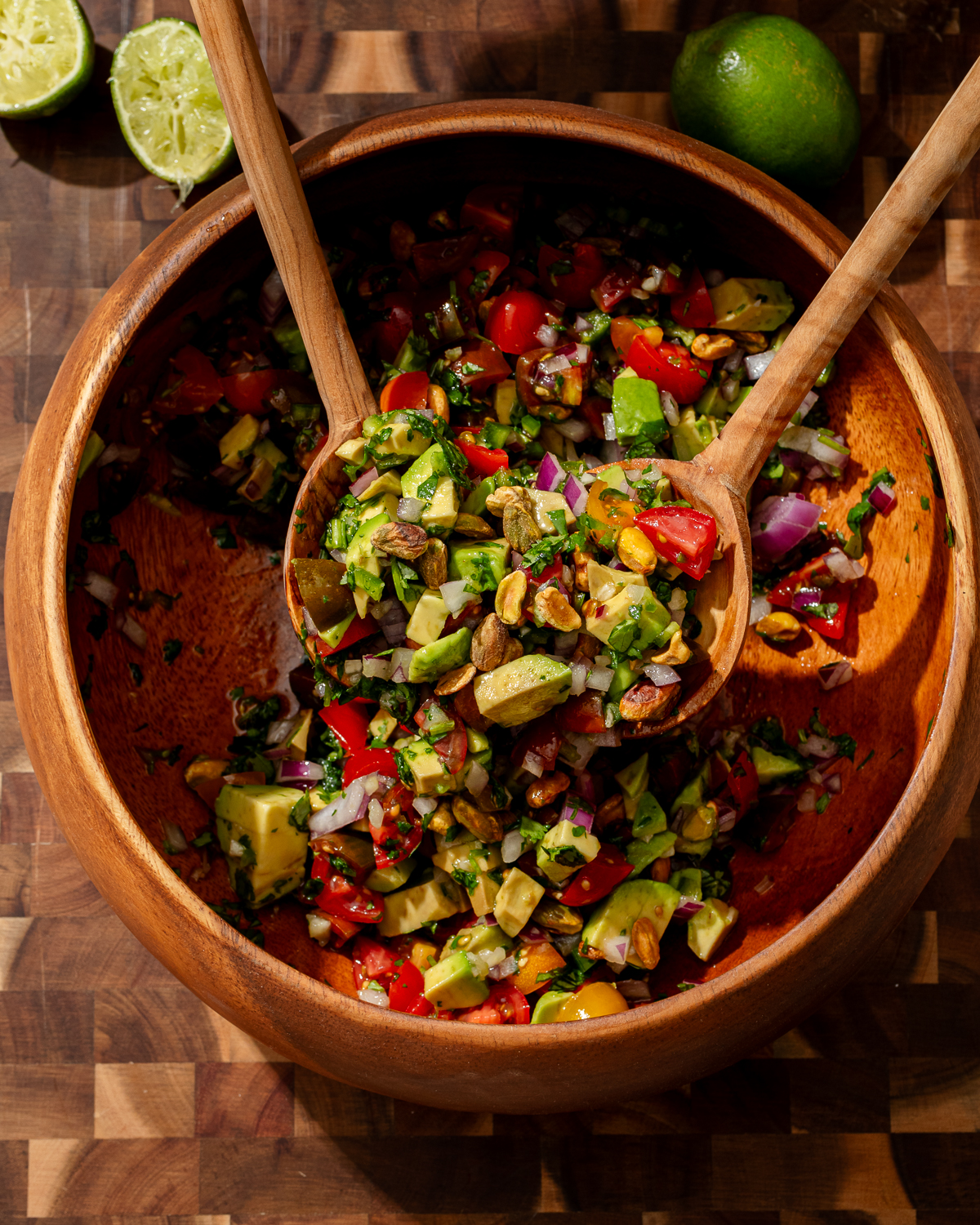 Creamy avocado salsa in a wooden bowl with salad spoons.