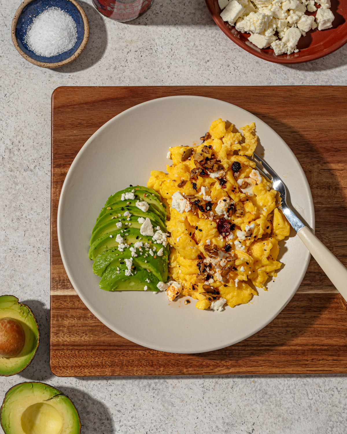 A serving of scrambled eggs without milk on a cutting board with sides and toppings.