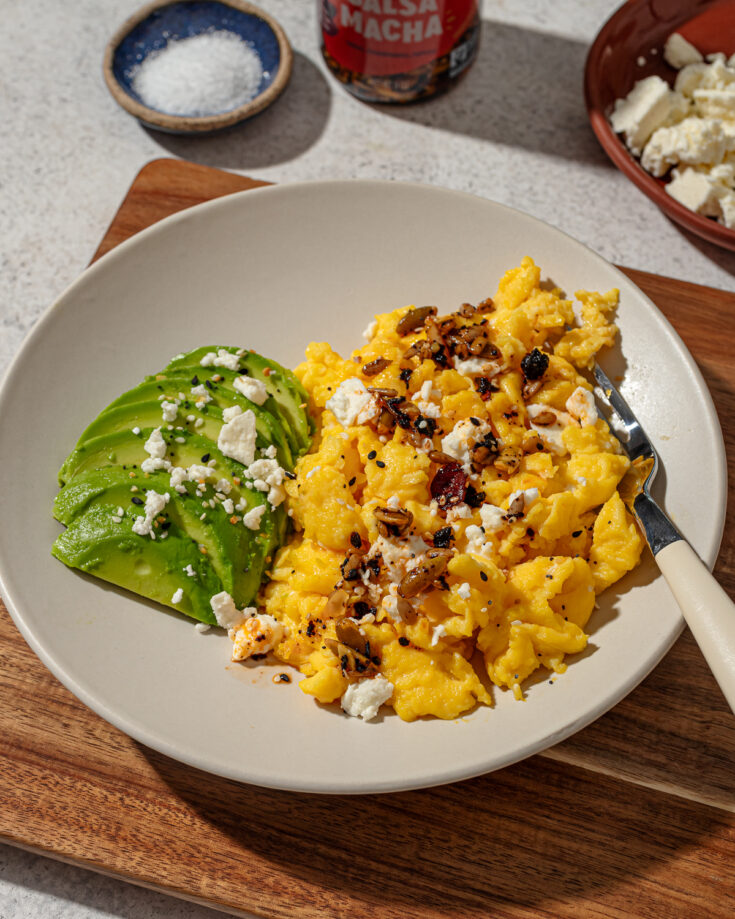 Scrambled eggs without milk on a gray plate with sides and toppings.
