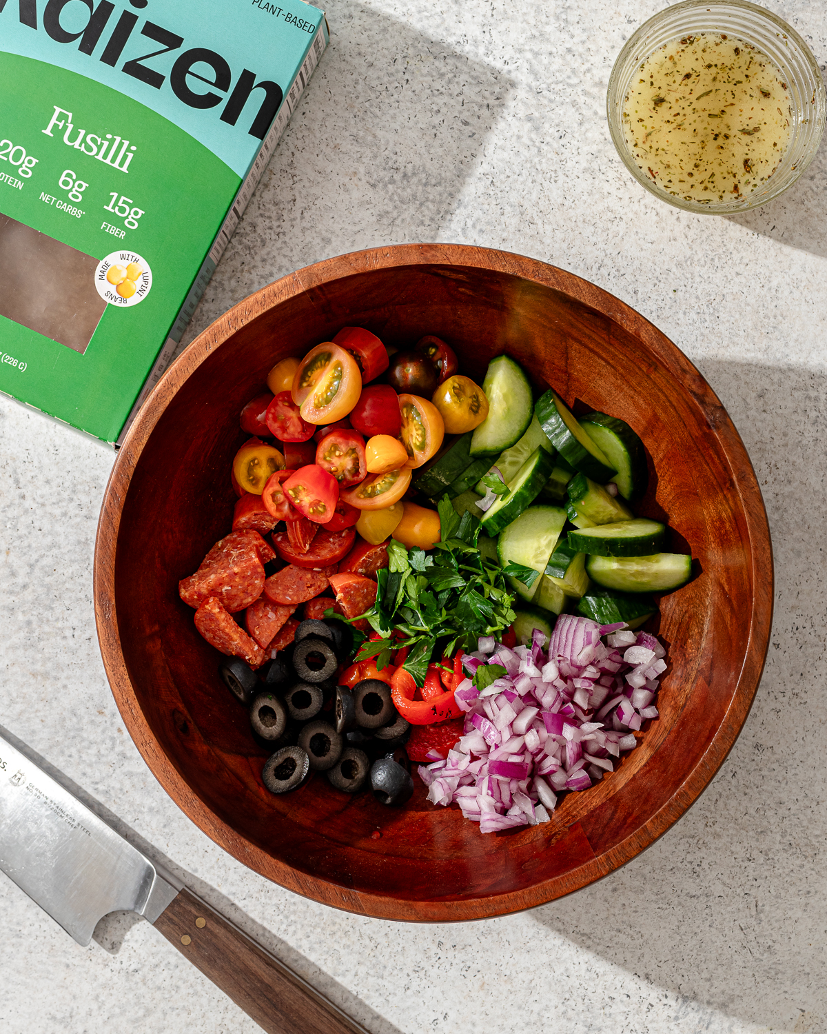 Ingredients for high protein pasta salad in a wooden bowl.