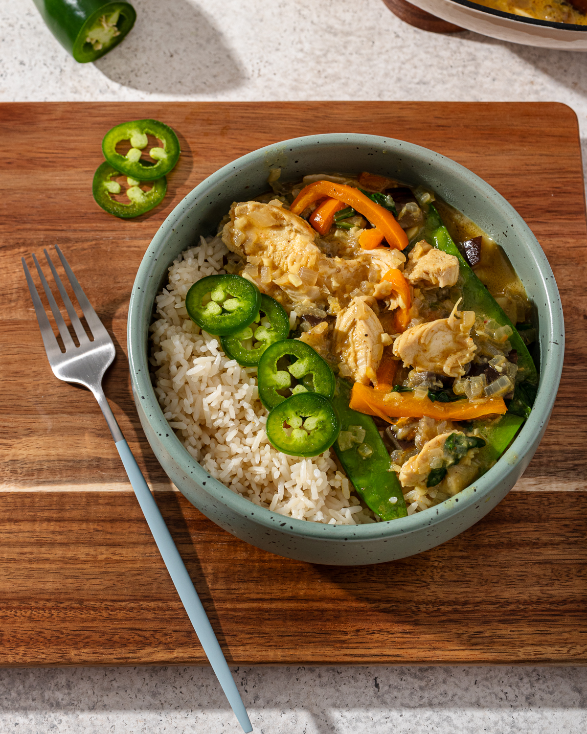 A serving of keto Thai curry in a blue bowl with toppings.