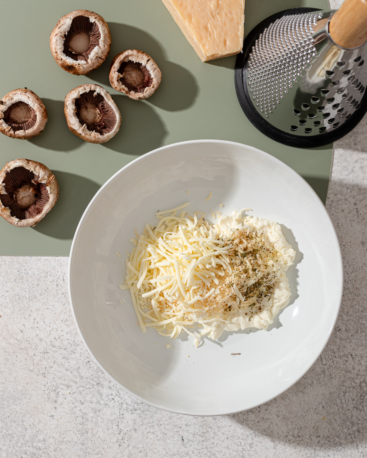 Ingredients for stuffed mushrooms with ricotta in a white bowl.