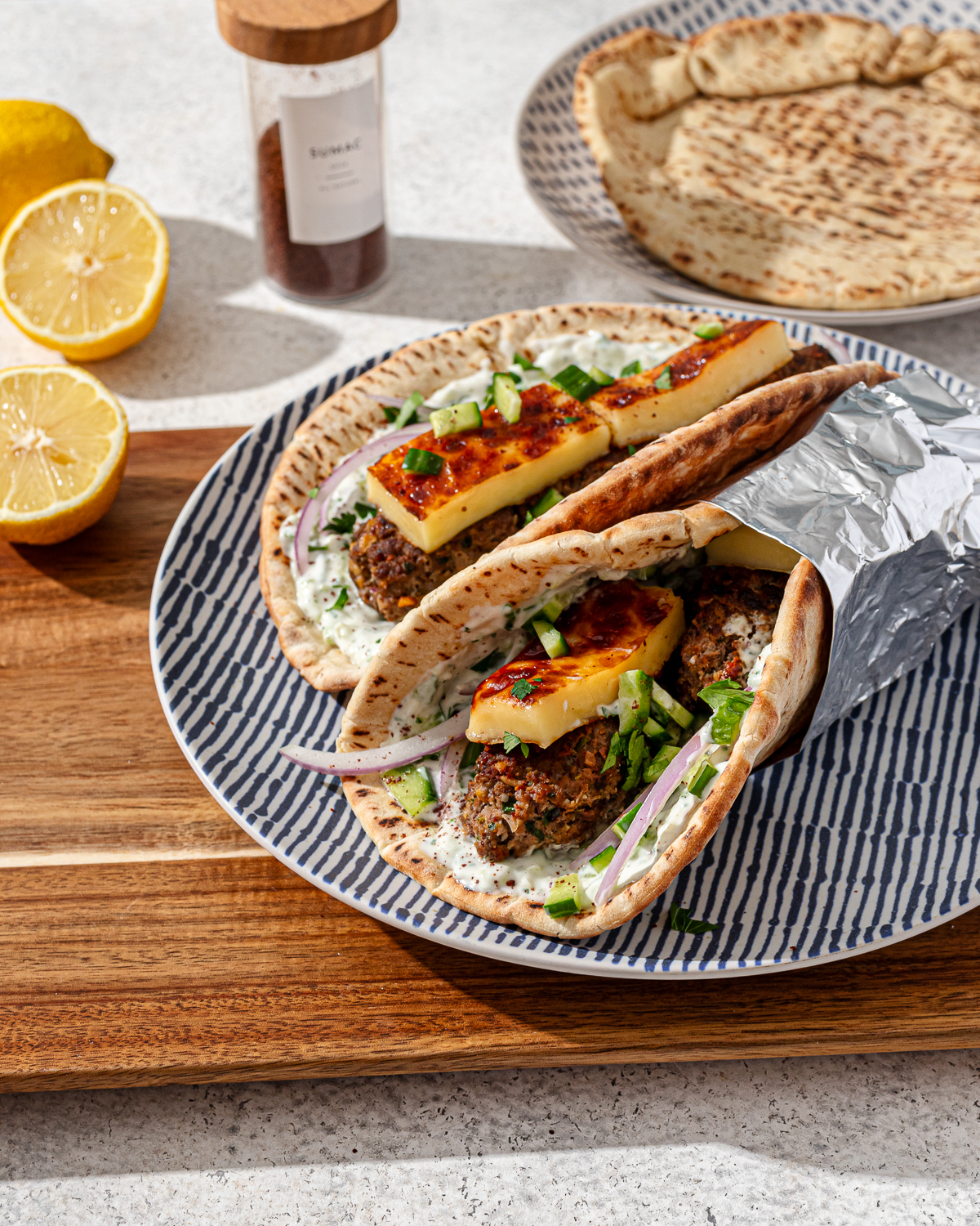 Kofta wrap on a striped plate over a cutting board.