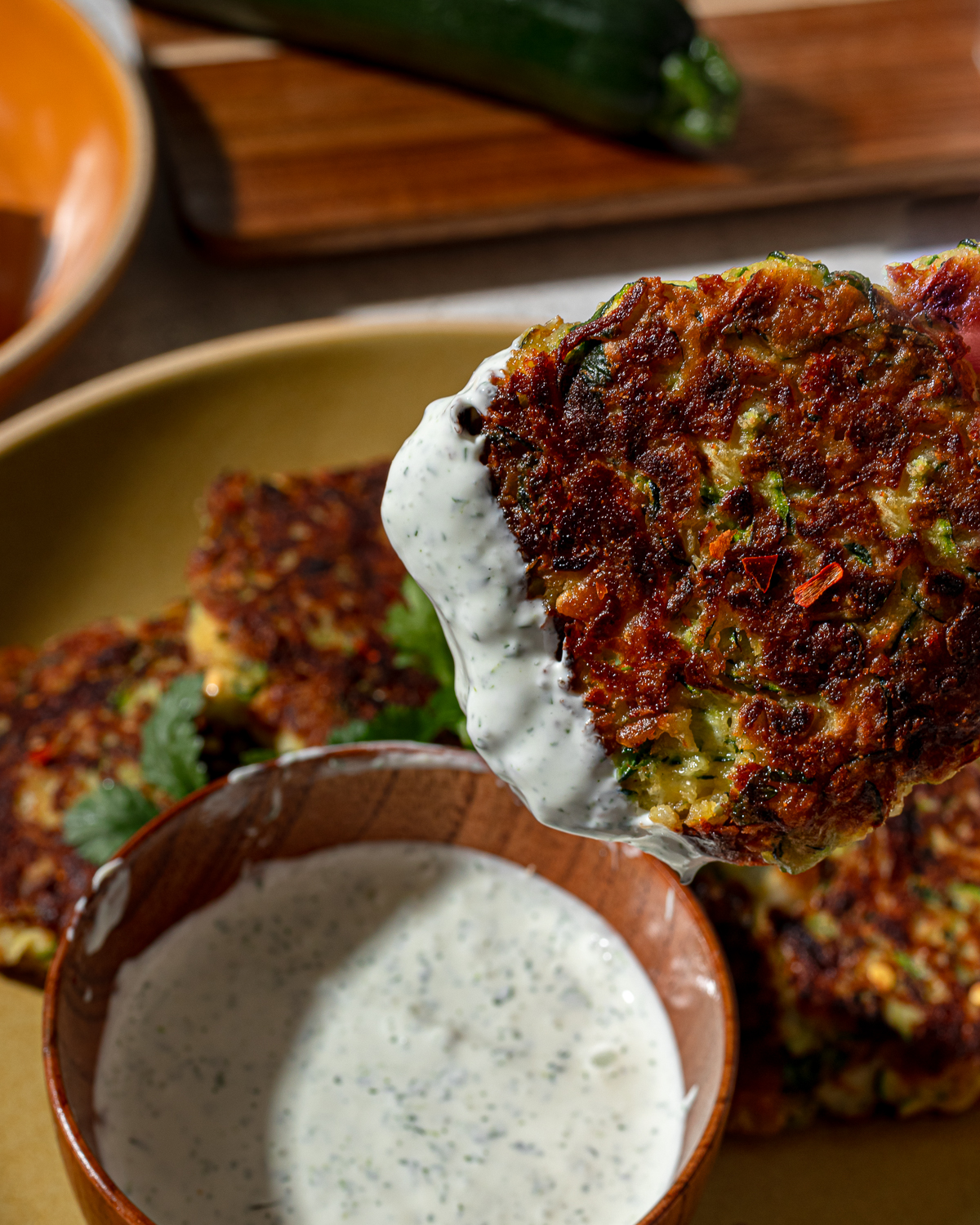 Close-up of zucchini fritters dipped in sauce.