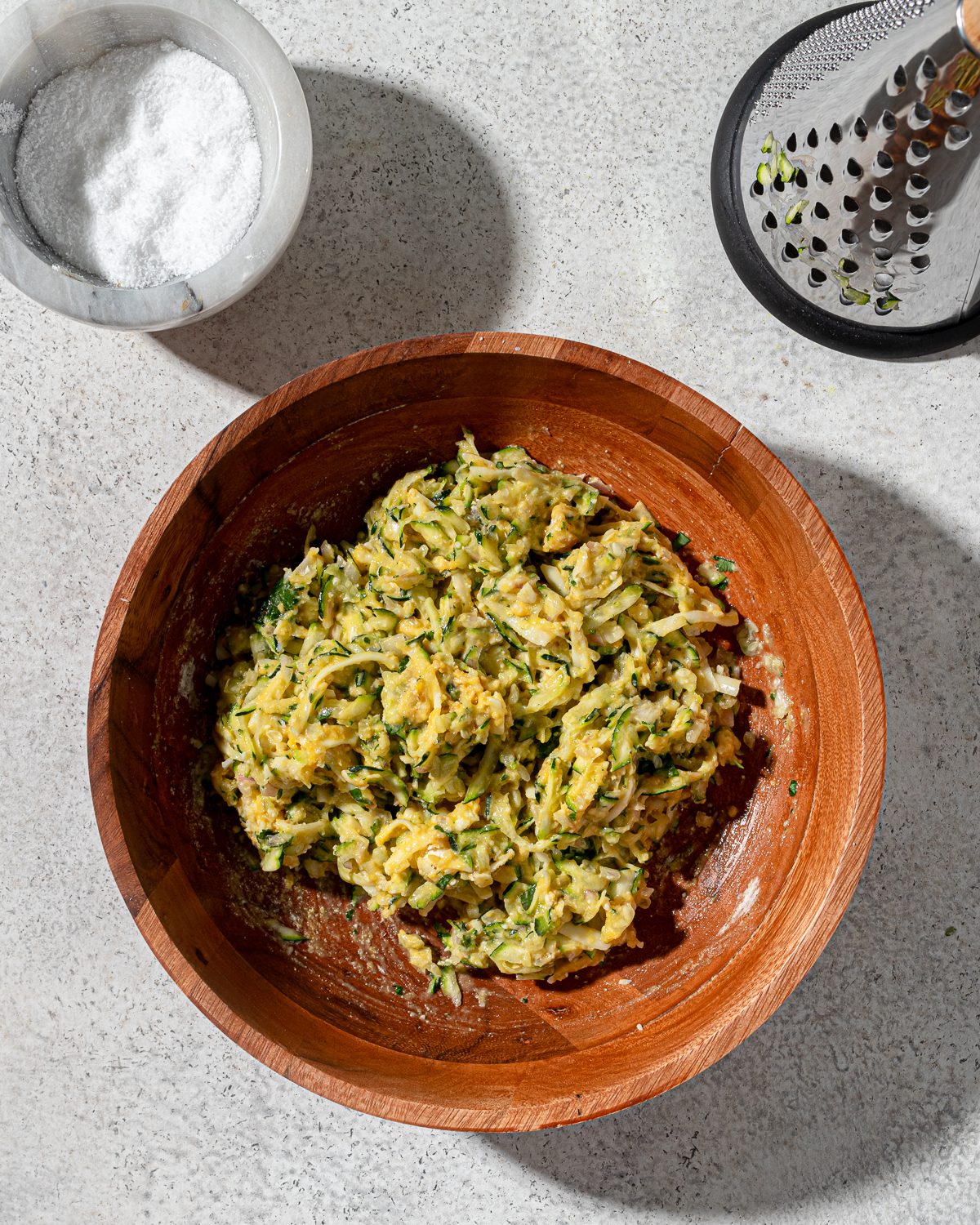 Zucchini fritters mix in a wooden bowl.