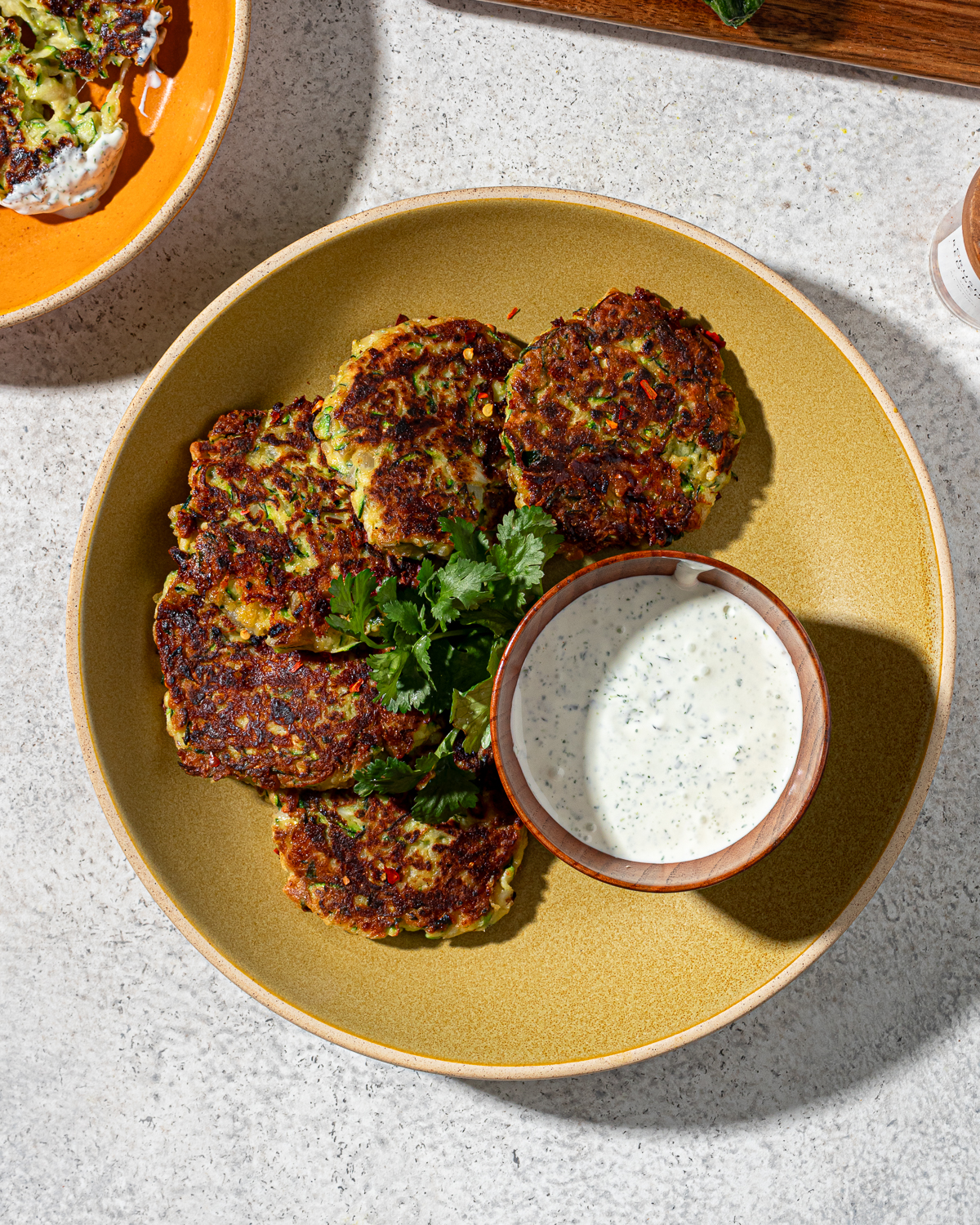 Low-carb zucchini fritters in a mustard colored plate with sauce.