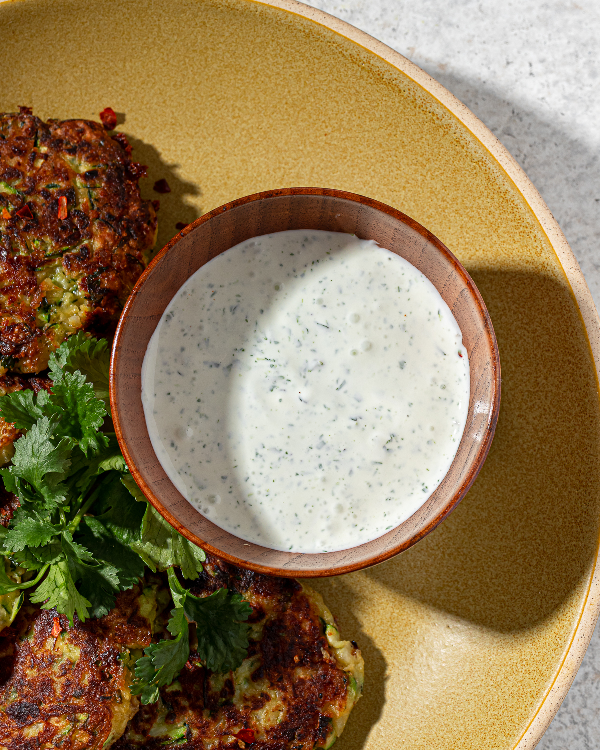 Creamy dip for zucchini fritters in a ramekin.