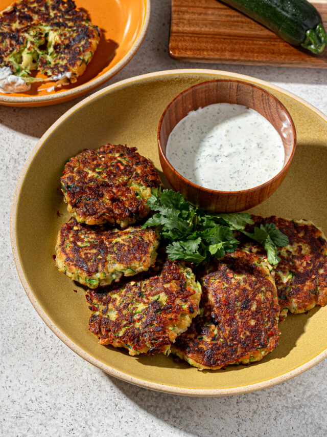 Zucchini fritters in a mustard colored dish with dip.