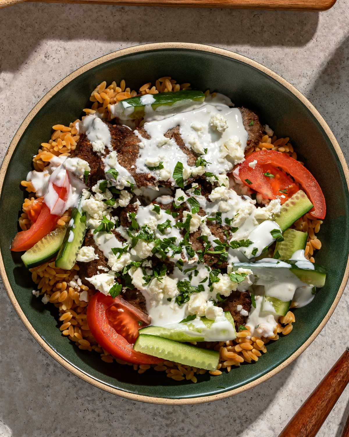 Close-up of gyro bowl recipe in a green bowl over a gray marble surface.