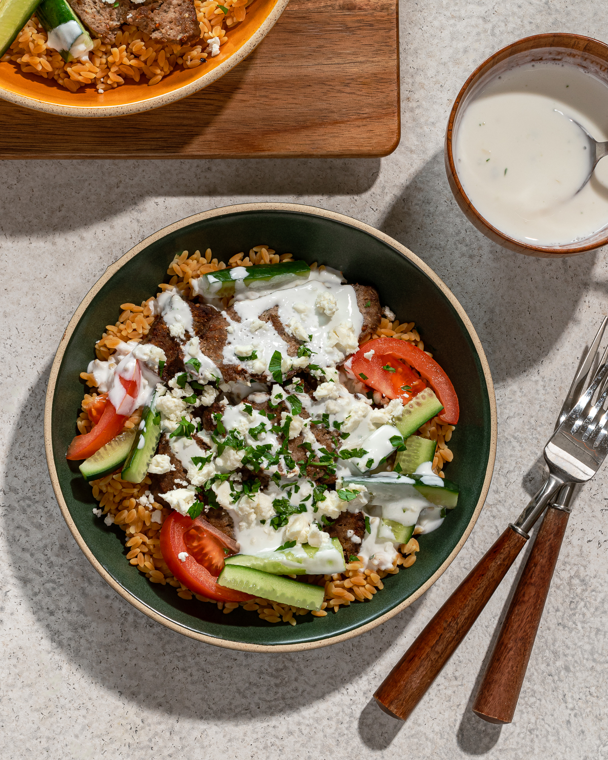 A serving of gyro bowl recipe with sauce, fork, and toppings over a gray marble surface.