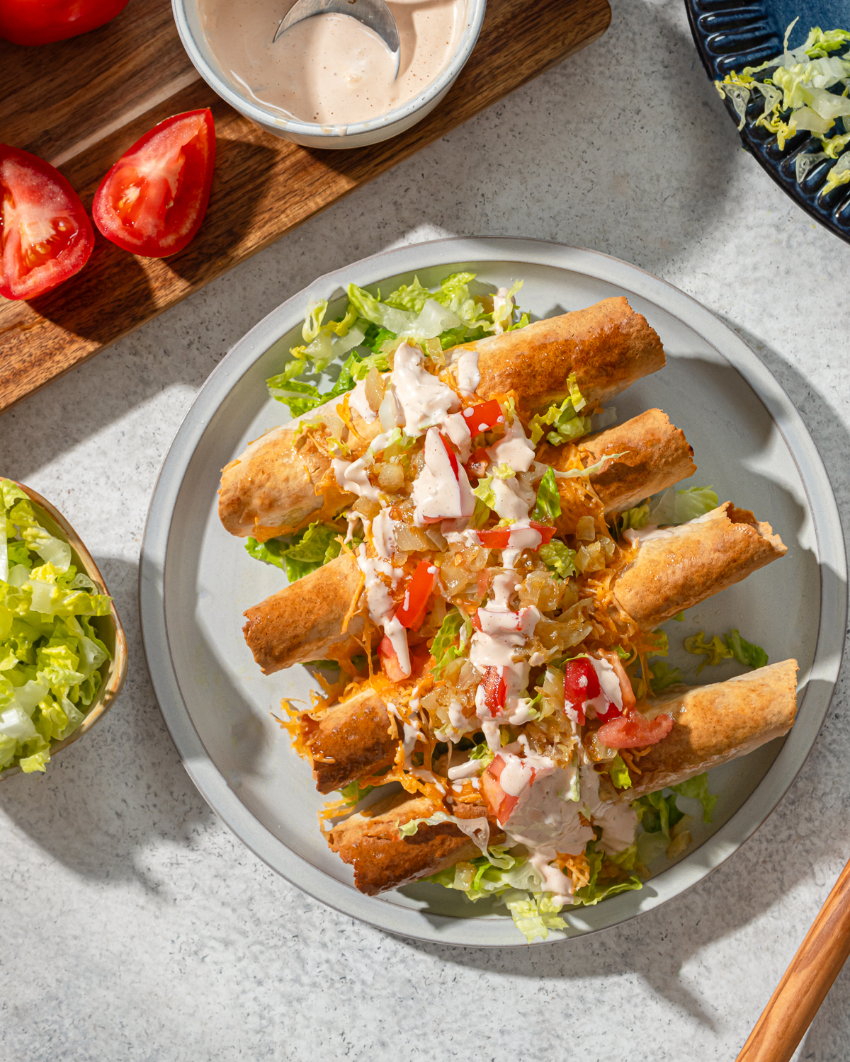 A serving of low carb taquitos in a gray plate with sauce and toppings.