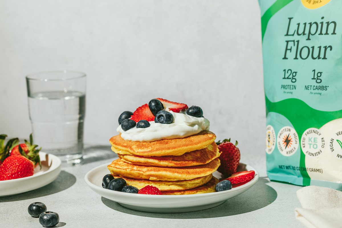 A serving of lupin flour pancakes with whipped cream and berries.