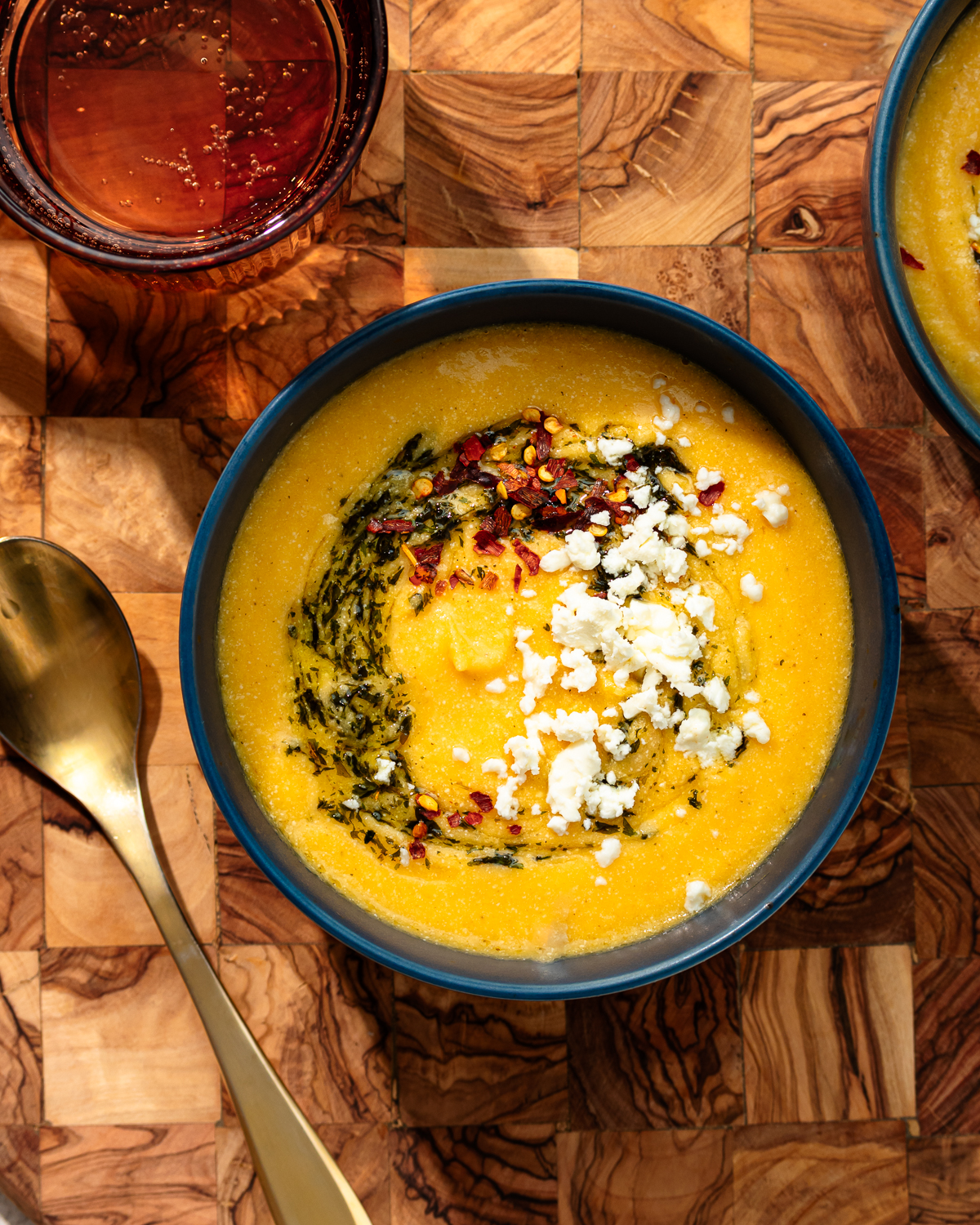 Roasted feta soup in a black bowl over a wooden surface.