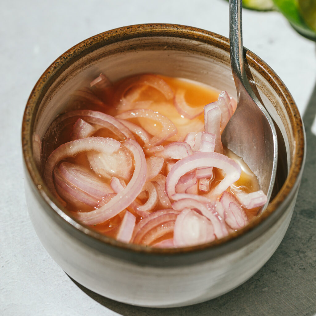 quick pickled shallots in a stainless steel container