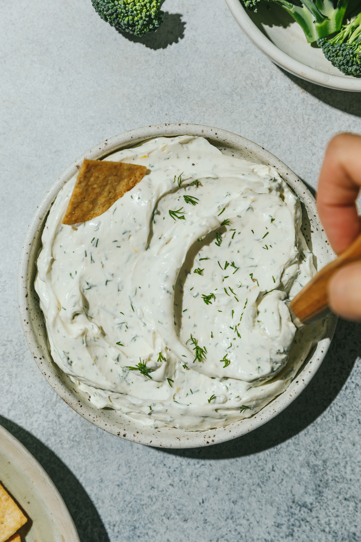 Stirring dill cream cheese spread in a serving dish.