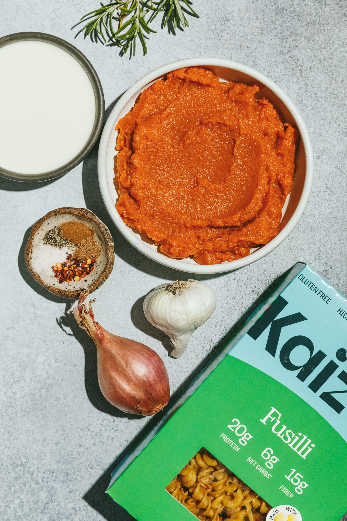 Ingredients for healthy pumpkin pasta on a gray surface.