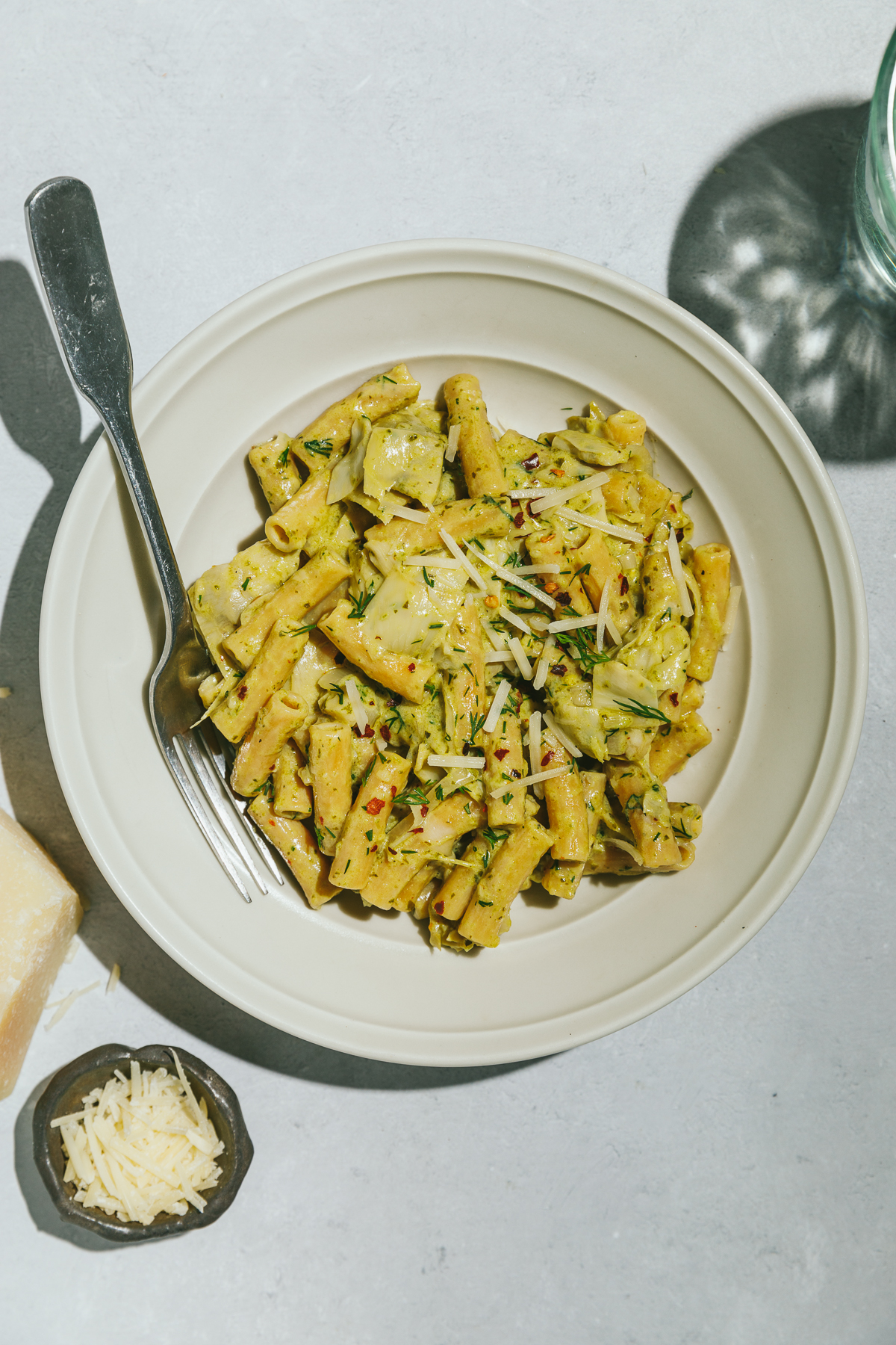 pesto artichoke pasta in a beige bowl.